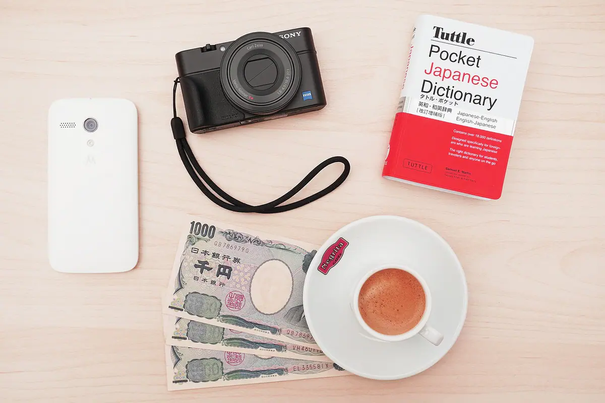 Cámara, teléfono, dinero y café sobre una mesa de trabajo