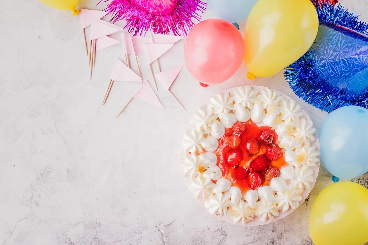 Pastel de cumpleaños rodeado de globos y banderines de colores