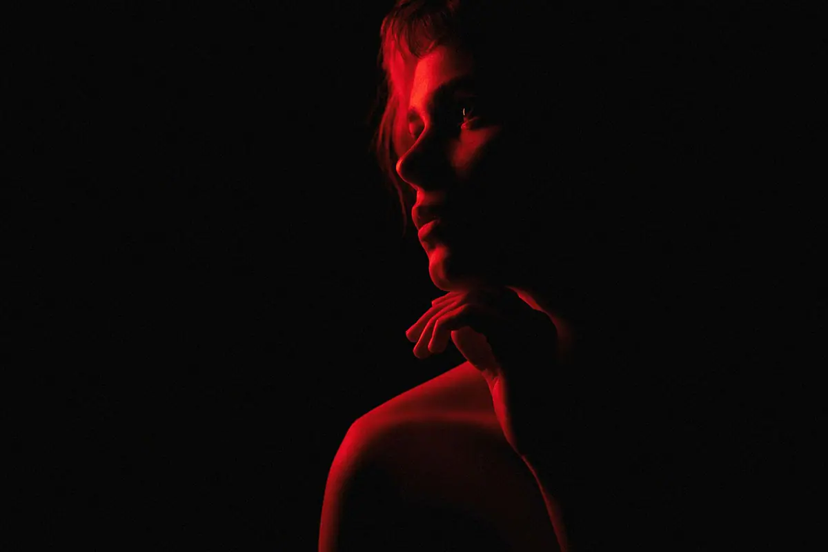 Perfil de un rostro iluminado con trazos de luz sobre fondo oscuro