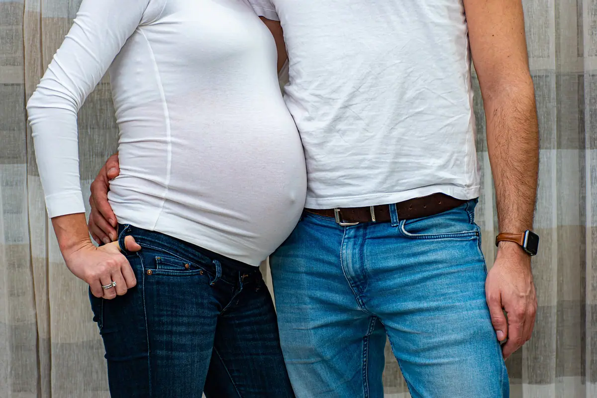 Pareja abrazándose durante una sesión fotográfica de embarazo