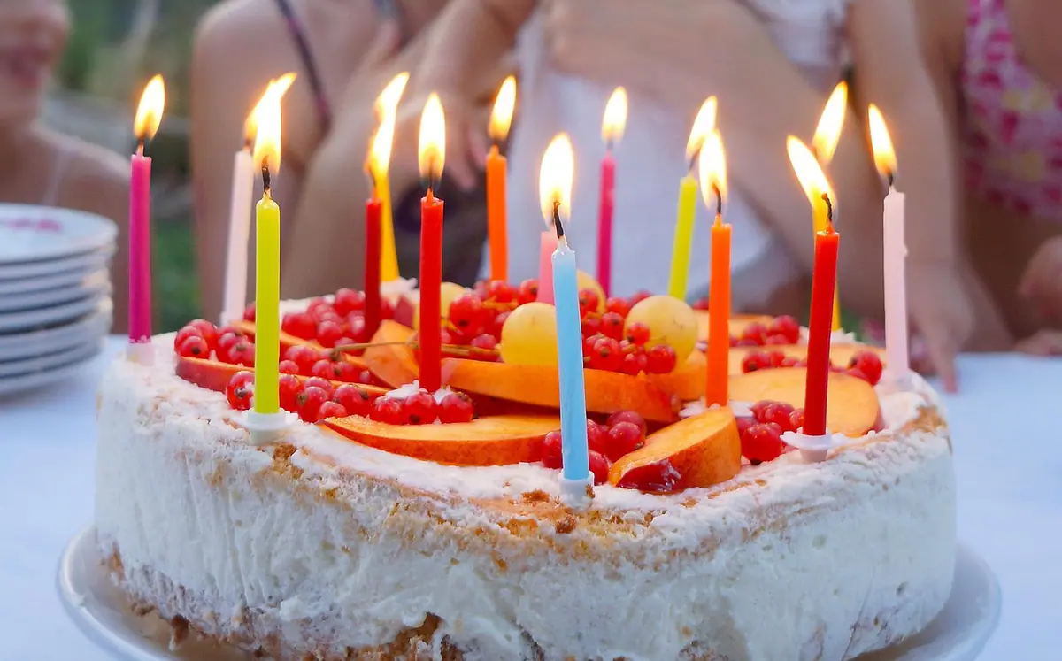 Persona posando junto a su pastel durante una sesión de cumpleaños