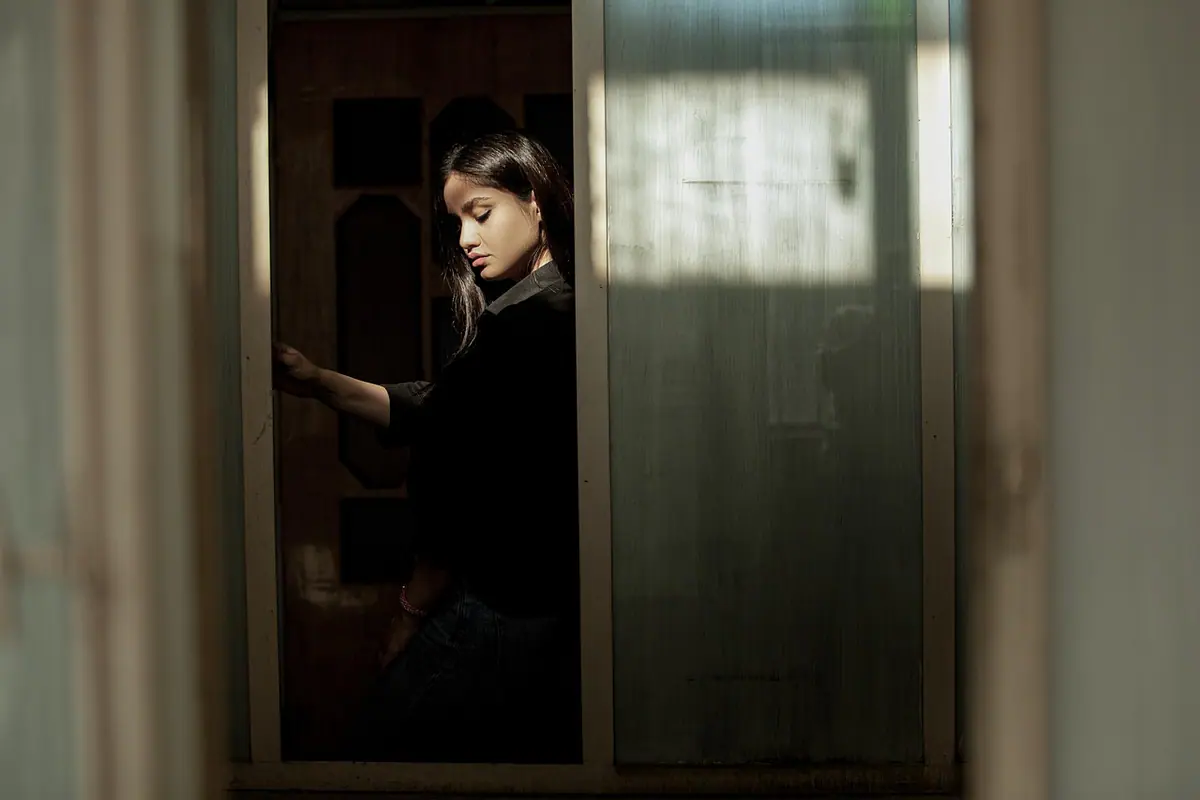 Mujer posando en casa junto a una ventana