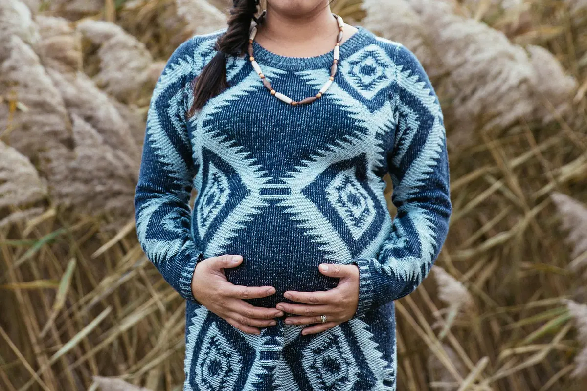 Mujer embarazada posando con un vestido largo de maternidad